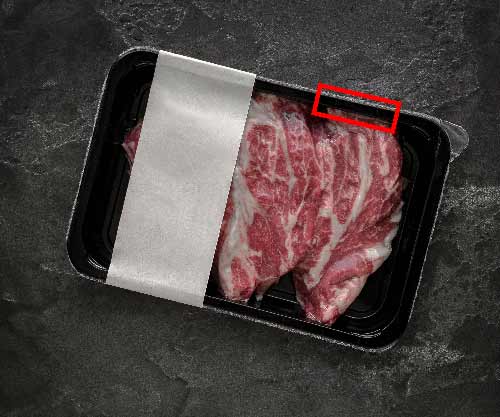 Abbildung einer Kunststoffverpackung von Steaks mit Fokus auf die Kleberversiegelung.